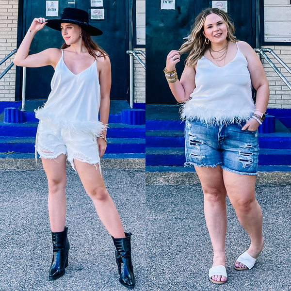 Models are wearing a white spaghetti strap top that has feather trim. Size small model has it paired with white crystal shorts, black booties, and a black felt hat. Size large model has it paired with distressed denim shorts, white sandals, and gold jewelry.
