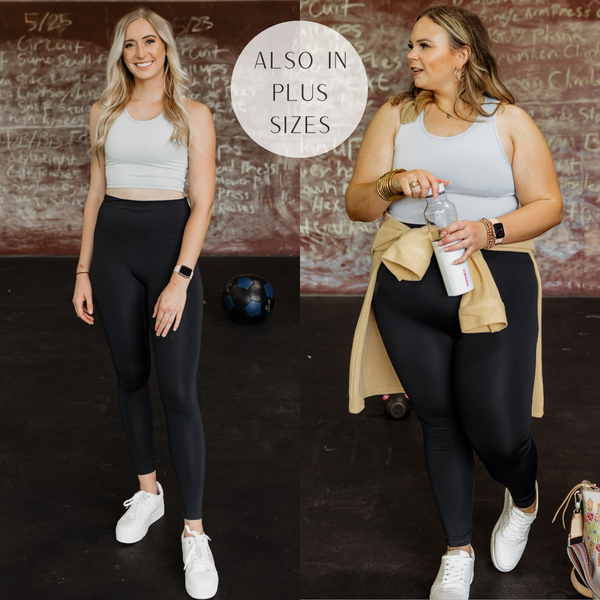 Models are wearing a light grey sports bra that has an open back. Both models have it paired with white sneakers and black leggings.