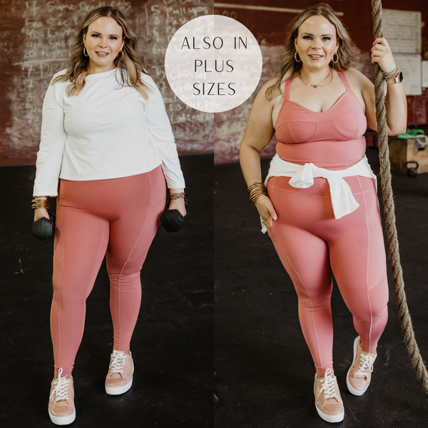 Model is wearing a pair of mauve pink leggings with pockets on the sides. Model has them paired with blush pink sneakers, a matching sports bra, and a white cropped top.