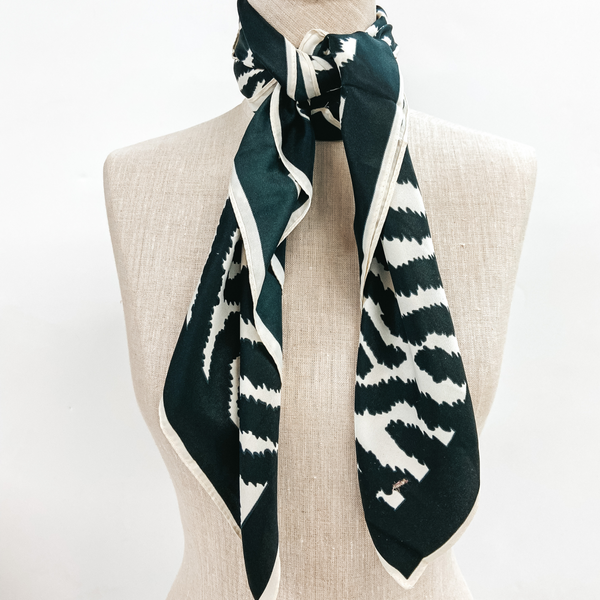 A zebra print scarf tied around the neck of a mannequin. Pictured on white background.