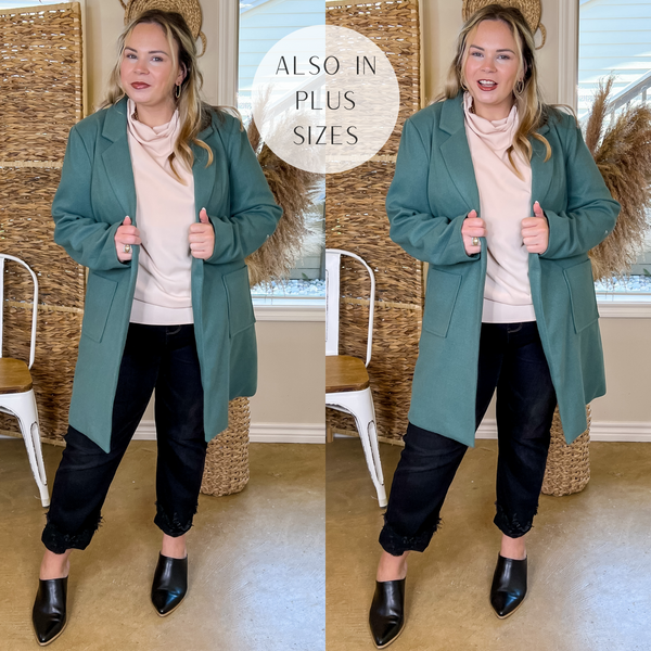 Model is wearing an open front long teal coat. Model has this collared coat paired with a beige top, black jeans, black mules, and gold jewelry.