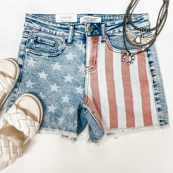 A pair of striped and star print light wash shorts. Pictured with white buffalo jewelry and white sandals.