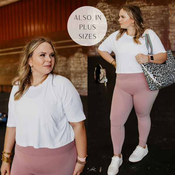 Model is wearing a white crop top with a front pocket. Model has it paired with light pink leggings, white sneakers, and a leopard print bag.