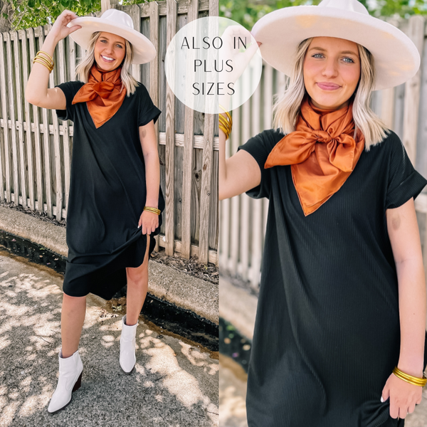 Model is wearing a short sleeve, ribbed midi dress in black. Model has it paired with white booties, a white hat, and a orange wild rag. 
