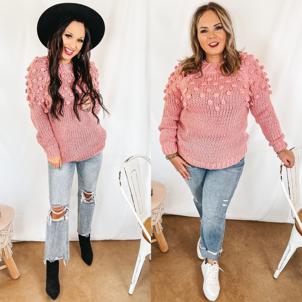 Models are wearing a pink long sleeve sweater that has a puff ball upper. Size small model has it paired with light wash jeans, black booties, and a black hat. Size large model has it paired with light wash jeans, white sneakers, and silver earrings.