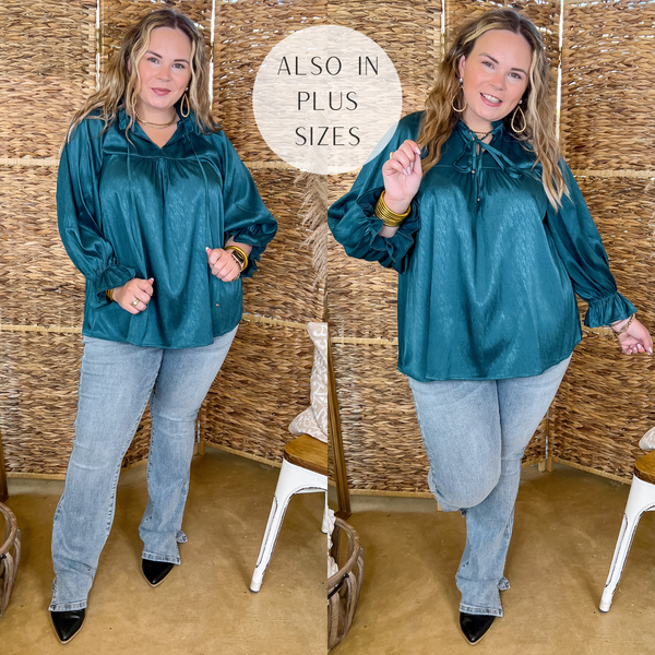 Model is wearing a teal blue long sleeve blouse with a front tie keyhole. Model has it paired with light wash bootcut jeans, black mules, and gold jewelry.