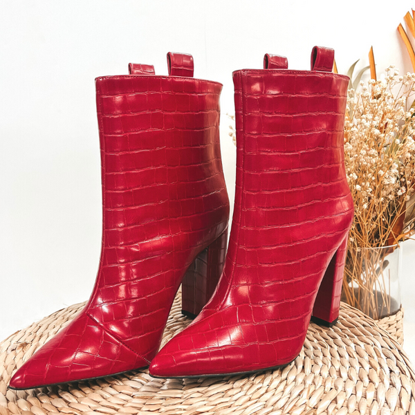 A pair of red croc booties with pull tabs at the top. Pictured on white background with basket weave display.
