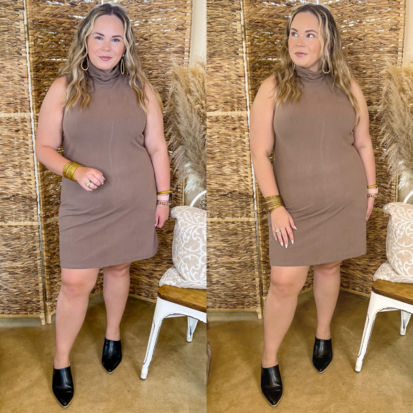 Model is wearing a taupe short dress with tank top straps and a turtle neck. Model has this sweater dress paired with black mules and gold jewelry.