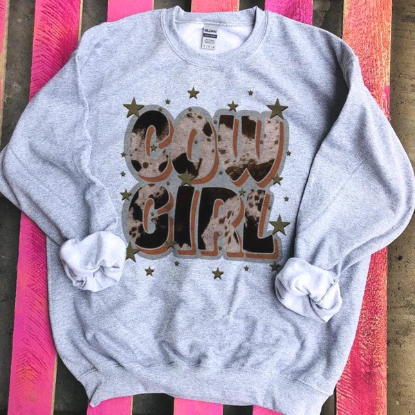A grey colored sweatshirt with a graphic that says "Cowgirl" in a cowhide print with stars.