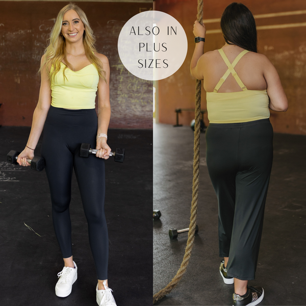 Models are wearing a yellow tank top sports bra with adjustable straps. Size small model has it paired with black solid leggings, white sneakers, and gold jewelry. Plus size model has it paired with black sweatpants, black sneakers, and gold jewelry.