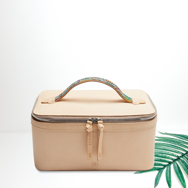 A leather train case cosmetic bag pictured on a white background with a palm leaf.