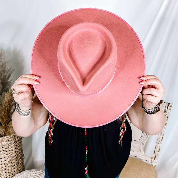 Model is holding a pink rancher hat infront of her face.  