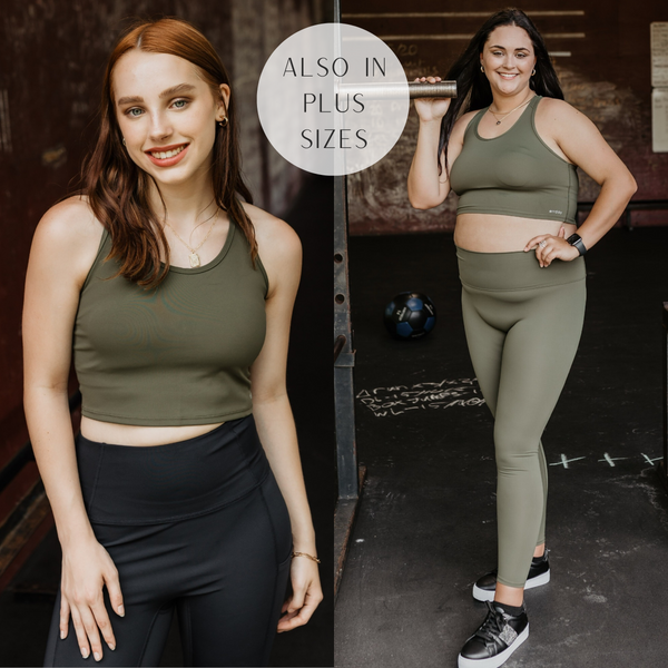 Models are wearing an olive green racer back sports bra. Size small model has it paired with black leggings and gold jewelry. Plus size model has it paired with matching olive green leggings and black sneakers.