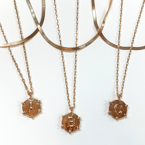Three gold, snake chain and paperclip chain necklaces with circle pendants. Each pendant has gold beads outlining the pendant with a centered gold initial. This picture includes the initials "A, B, and C." These necklaces are pictured on a white background.
