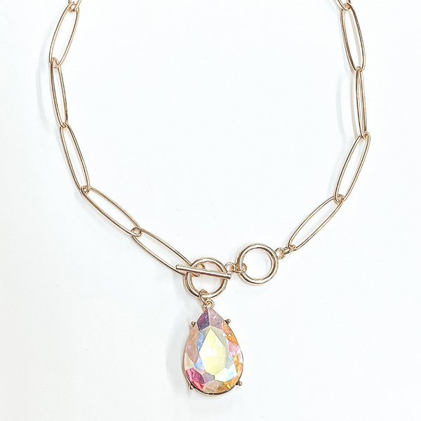 Gold, thin chain necklace with front toggle clasp. This necklace includes an AB teardrop crystal. This necklace is pictured on a white background. 