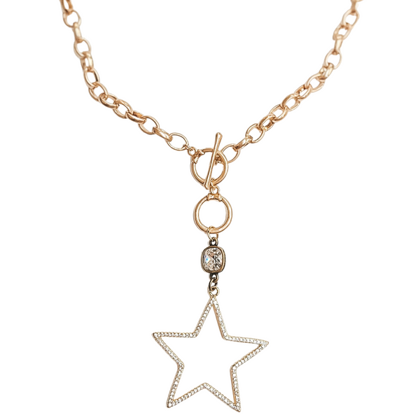  Gold chain necklace with front toggle clasp. This necklace includes a clear cushion cut drop crystal with bronze backing. Hanging from the crystal is a gold star pendant with clear crystals. This necklace is pictured on a white background. 