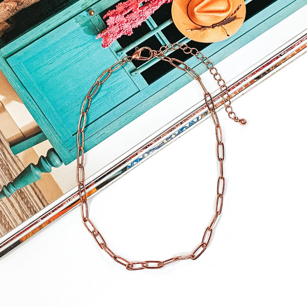 Copper paperclip chain necklace that is pictured half on a magazine and half on a white background.
