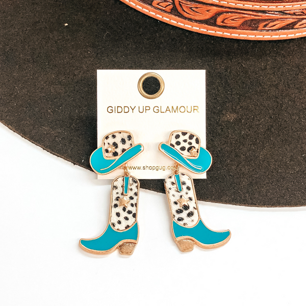 Hat stud earrings with a boot pendant drop. Both have a white and black dotted print with turquoise on the hat brim and on the foot part on the sock. These earrings are pictured on a white and brown background. 