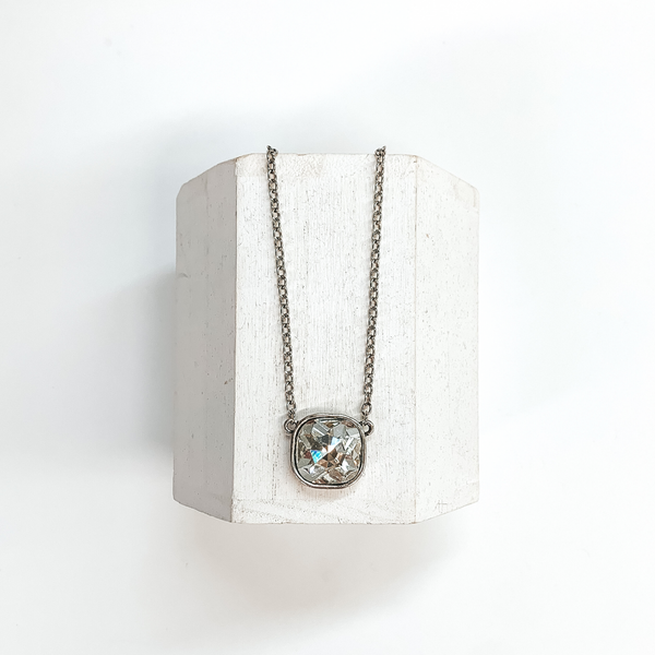This is a silver chain necklace with a clear cushion cut crystal pendant.  This necklace is taken on a white block and on a white background.