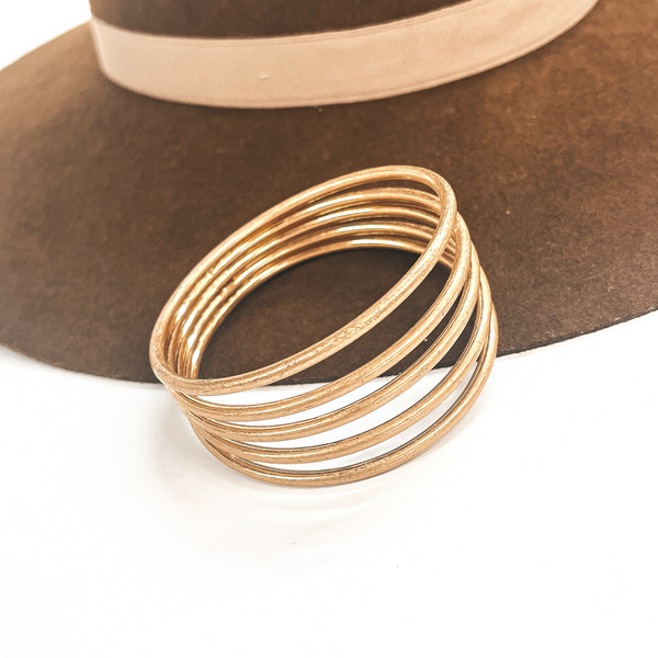 This is a five layered gold cuff bracelet, the bracelet connects in the  back, all five layers. This bracelet is taken on a dark brown brim hat  and on a white background.