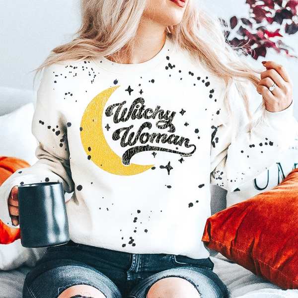 Model is wearing a white sweatshirt that reads "witchy woman" in black font with stars and a crescent moon. 