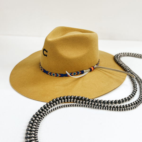 A mustard yellow felt hat with a blue beaded band with tribal patterns. Pictured on white background with Navajo Pearls.