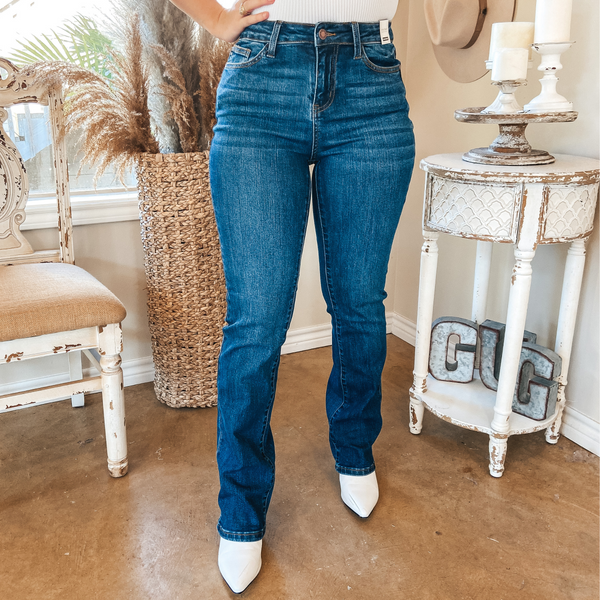 Medium wash long bootcut jeans. Pictured from waist down with white booties and white top.