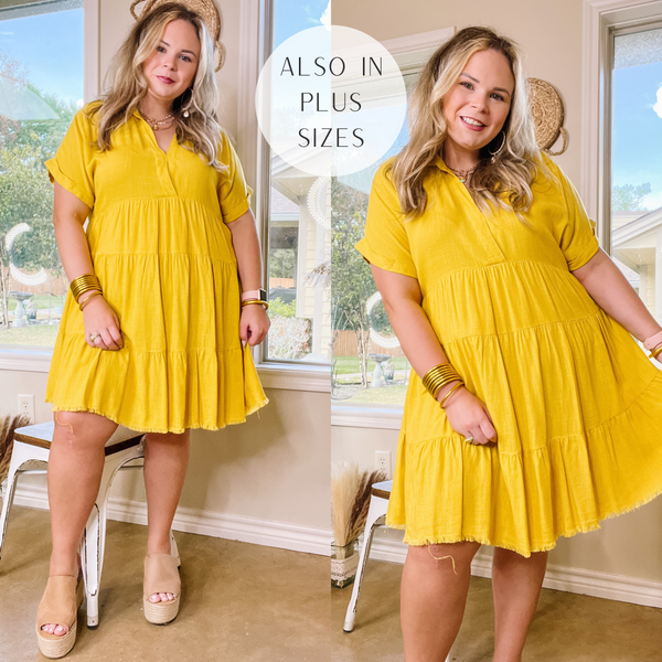 Model is wearing a yellow tiered dress with short sleeves and collared neckline. Model has it paired with tan wedges and gold jewelry.