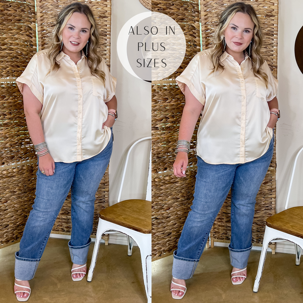 Model is wearing a cream color button up top with short sleeves. Model has it paired with cuffed jeans, white heels, and silver jewelry.