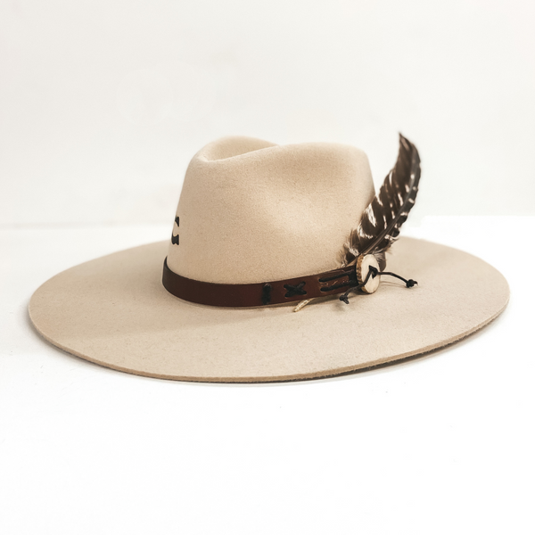 A light beige felt hat with a leather band. The hat includes a feather in the band. Pictured on white background.