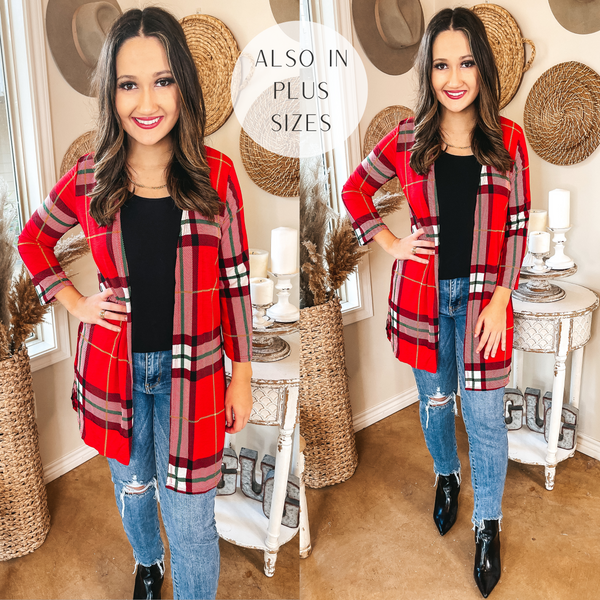 Model is wearing a plaid 3/4 sleeve cardigan that hits mid thigh. The plaid is a mix of red, green, yellow, black, and white. Model has it paired with distressed skinny jeans, black booties, and gold jewelry.