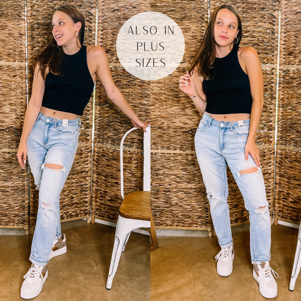 A pair of light wash boyfriend jeans that are cuffed and have distressing on the legs. Model has it paired with a black tank, white sneakers, and gold jewelry.