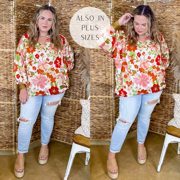 Model is wearing an ivory top with 3/4 sleeves, a notched neckline, and a pink and green floral print all over. Model has it paired with light wash distressed jeans, tan wedges, and gold jewelry.