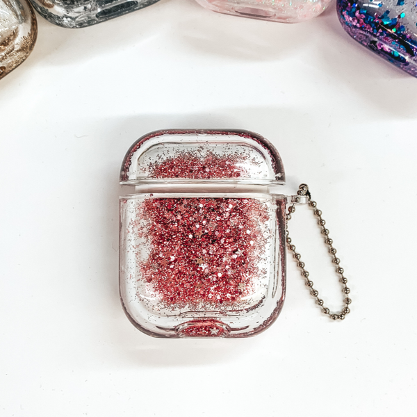 This is a clear airpod case filled with rose gold confetti inside the case. This case has a silver ball chain on one side. This case is pictured on a white background.