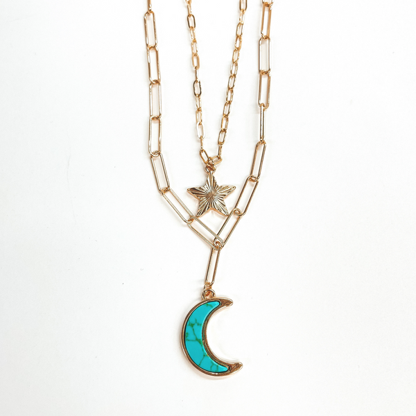 Double layered paperclip chain necklace in gold.  The shorter strand has a gold sunburst star and  the longer strand has a turquoise stone pendant in a moon shape. This necklace is taken on a white background.