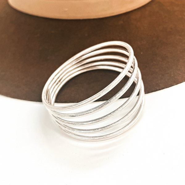 This is a five layered silver cuff bracelet, the bracelet connects in the  back, all five layers. This bracelet is taken on a dark brown brim hat  and on a white background.